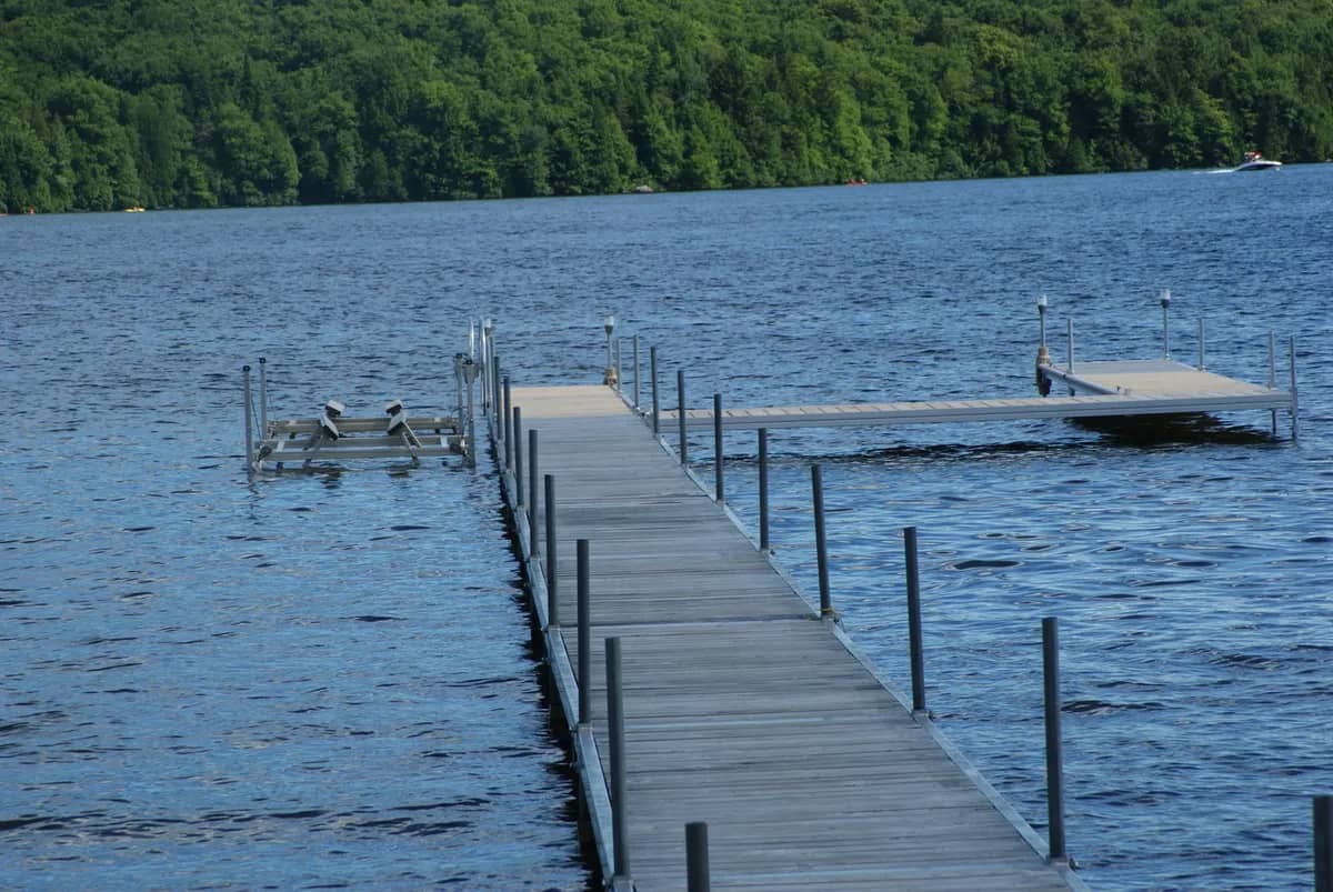 Dock with a small lift on a blue lake lined with forest